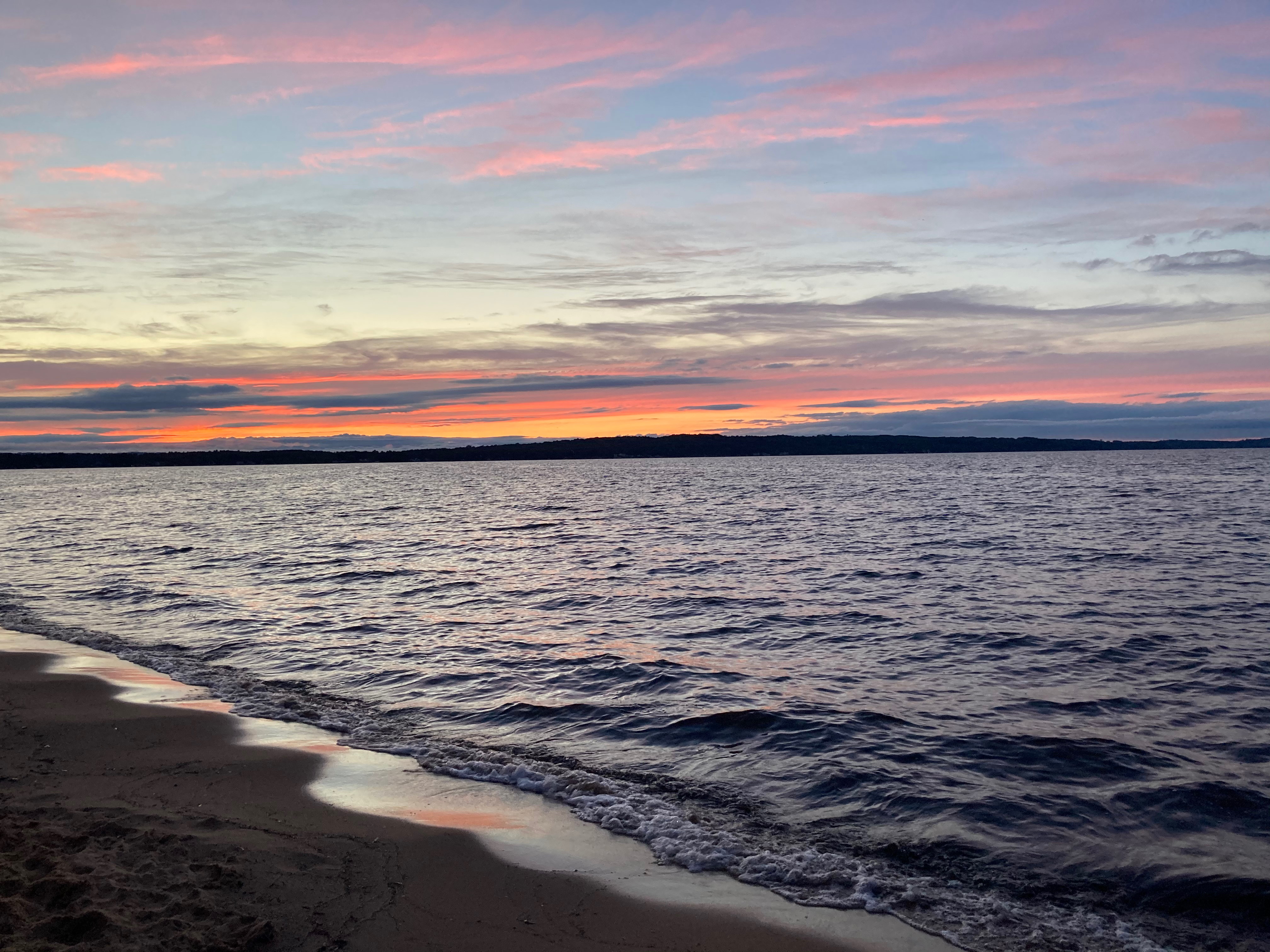 a beach at sunset with water and sand