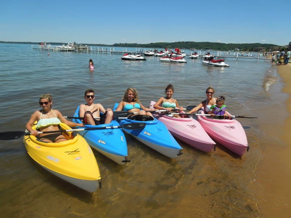 A group of people sitting in kayaks on a beach